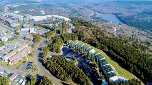 Ein Luftbild eines Resorts mit mehreren Gebäuden, einem Parkplatz und einem See, der von einem Wald umgeben ist.
