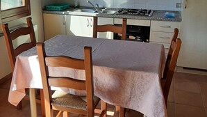 Eine Küche mit Esstisch, Stühlen, Schränken und einem Fenster.