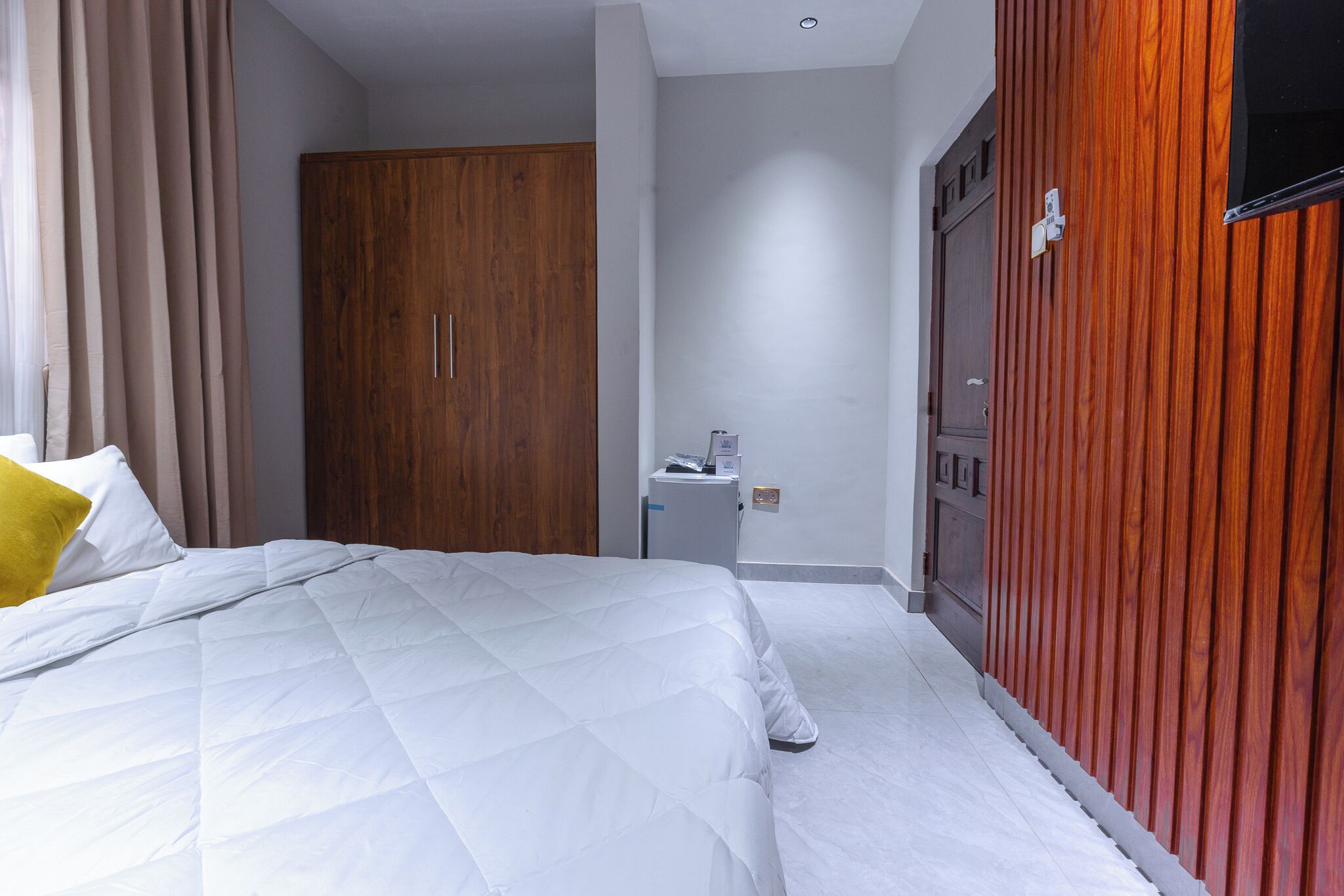 Ein Hotelzimmer mit einem großen Bett, einem Holzschrank, einem kleinen Schreibtisch und einem Schrank mit Spiegel.
