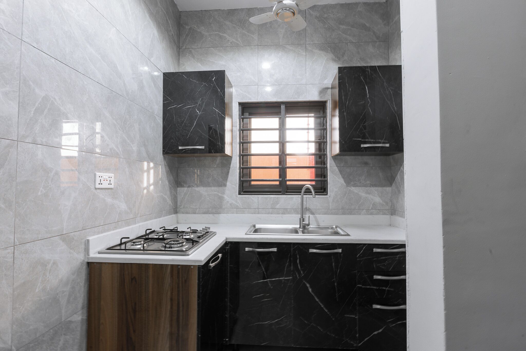 A kitchen with marble walls, a gas stove, a sink, and wooden cabinets.