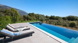 A rectangular swimming pool with a clear blue water surface, surrounded by a tiled deck. - Villa Antreas Mentoros (Kefalonia)