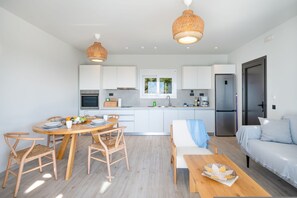 Une cuisine moderne avec des meubles blancs, un coin repas avec des meubles en bois et un salon avec un canapé et une table.