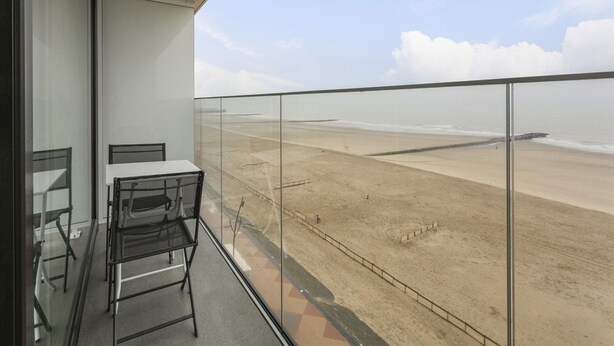 A balcony with a glass railing overlooking a beach. - Apartment in Blankenberge With Sea Views (Blankenberge)