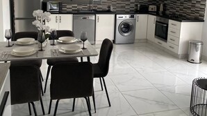 A modern kitchen with white cabinets, a dining table set for four, and a washing machine. - Luxury 3 Bedroom Penthouse apartment with sea view.
10 mins walk to Venus Beach (Paphos)