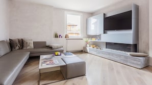 Un soggiorno moderno con un divano, un tavolino e una TV a parete.
