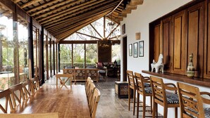 Un vaste espace dédié à la salle à manger, avec une table et des chaises en bois, de grandes fenêtres et une structure de plafond en bois.