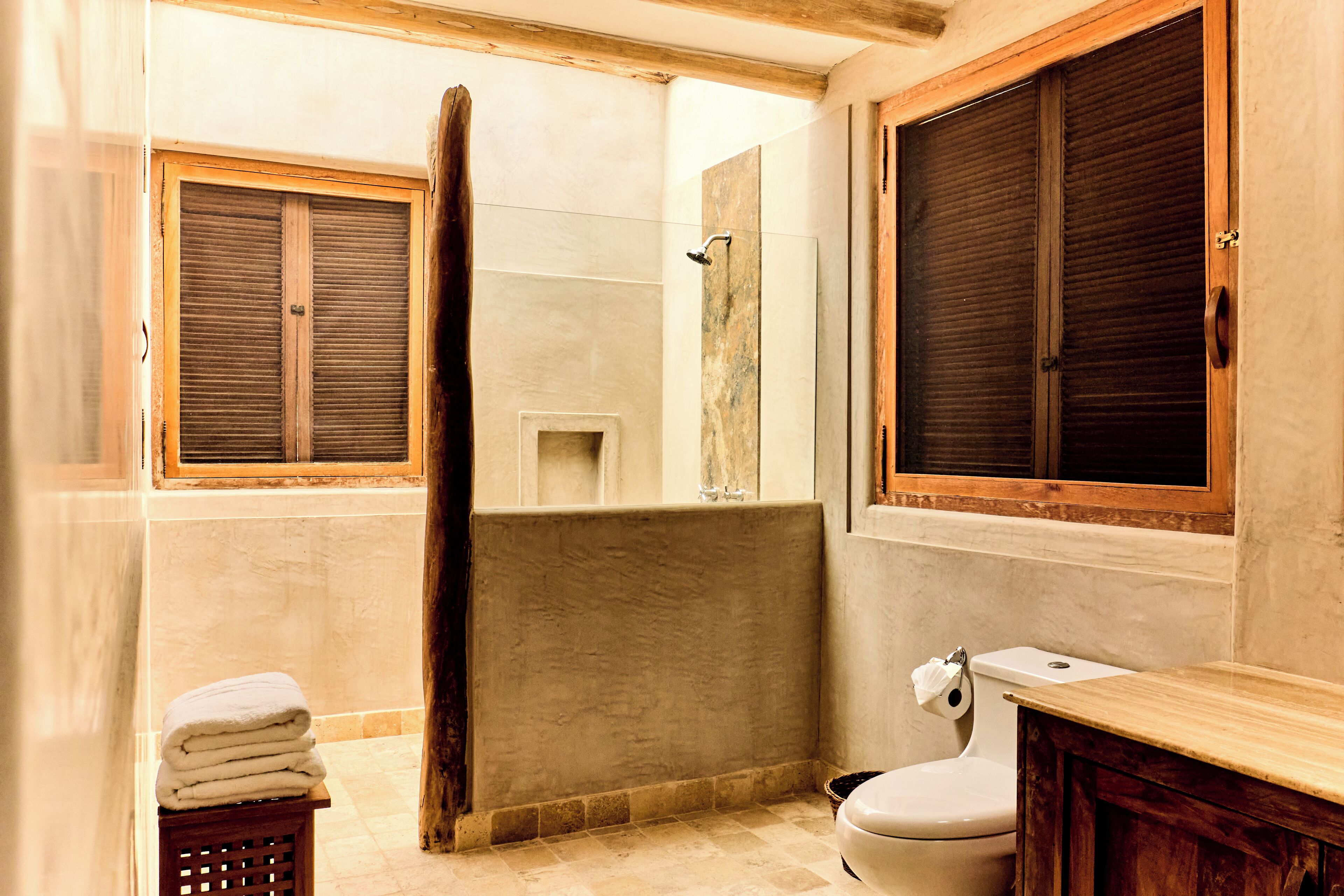 A bathroom with a bathtub, toilet, and a window with wooden shutters.