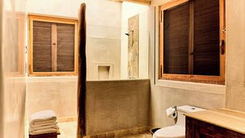 A bathroom with a bathtub, toilet, and a window with wooden shutters.