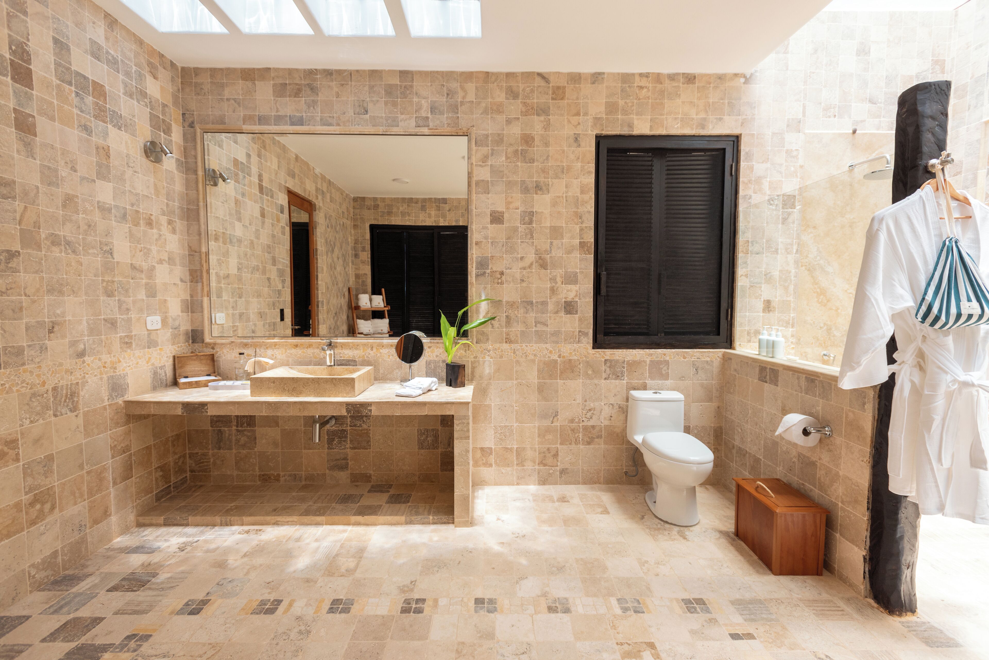 A modern bathroom with a large mirror, a sink, a toilet, and a bathtub.