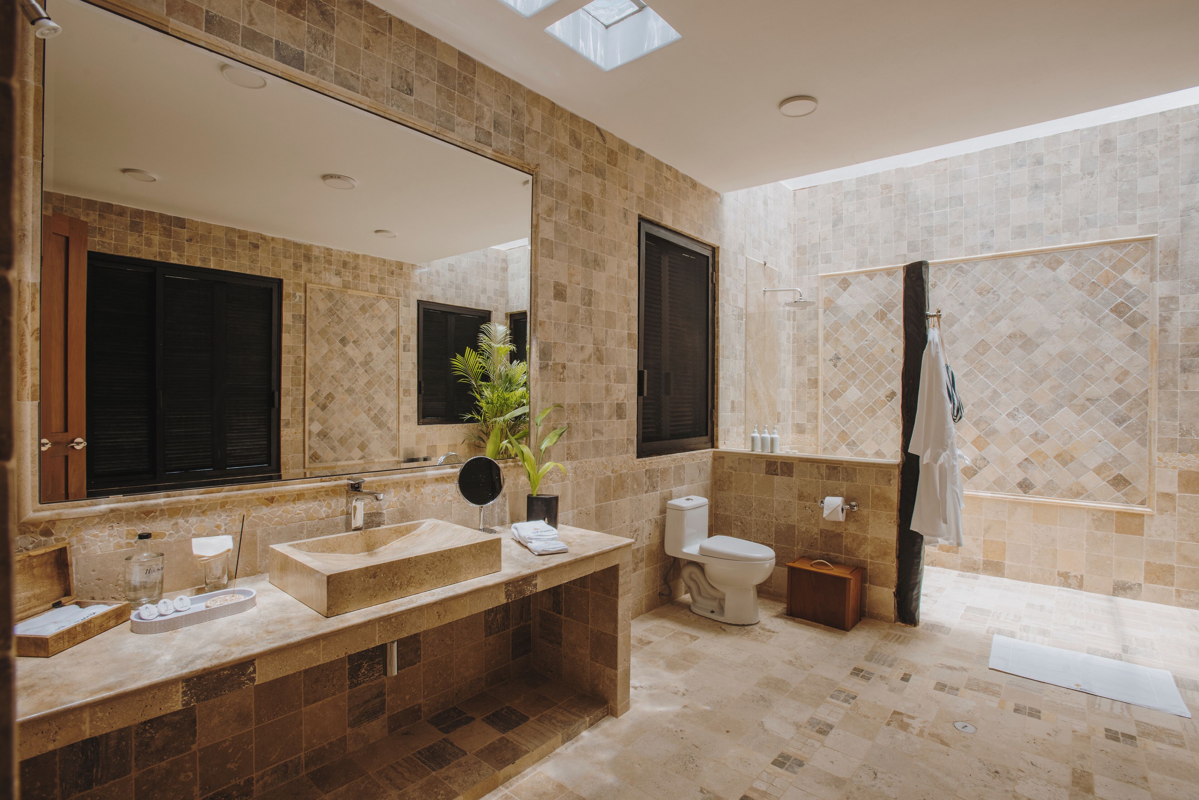 A modern bathroom with a large mirror, a sink, a toilet, and a shower area.