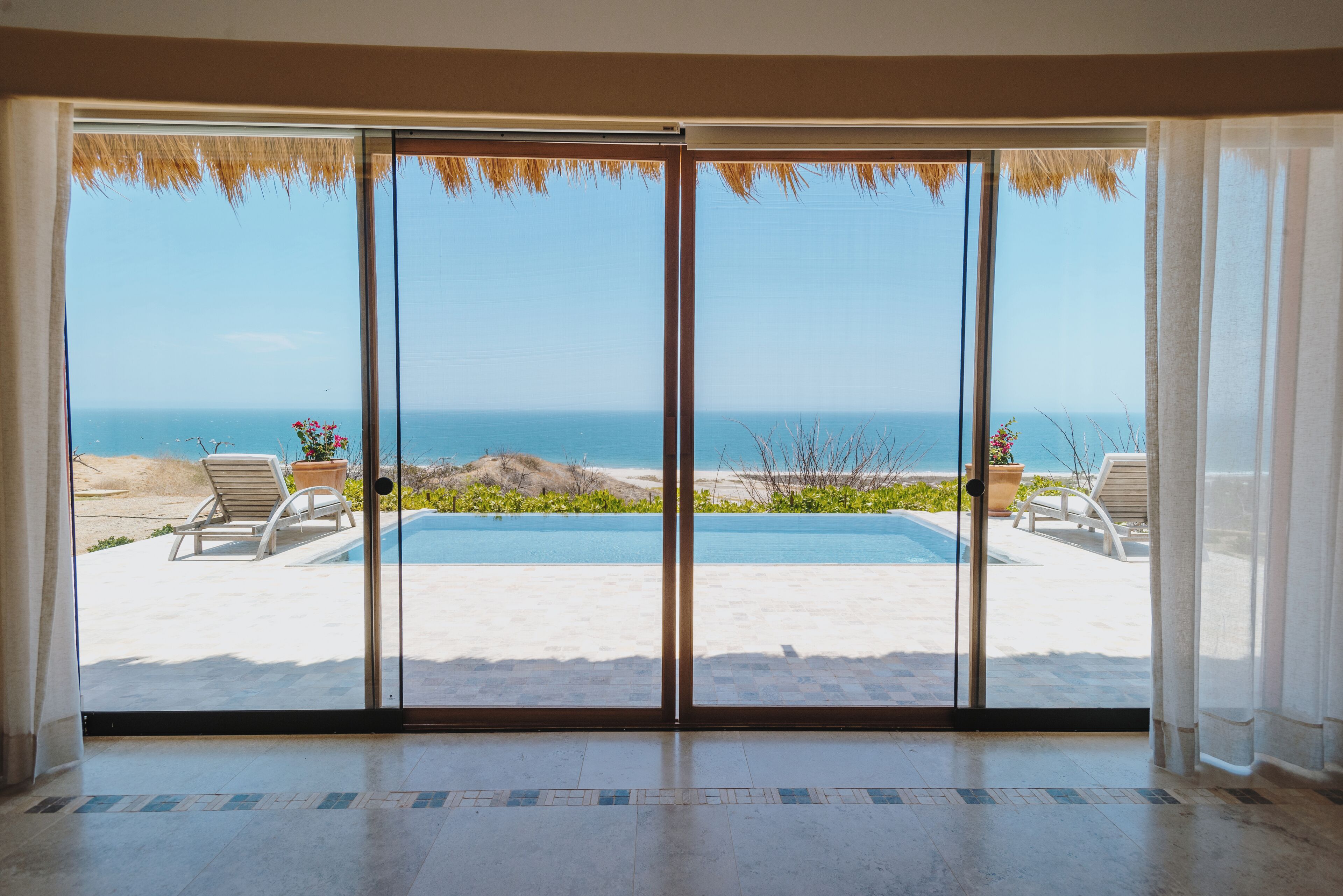 Una habitación con puerta de vidrio que da a una vista de la piscina y la playa.