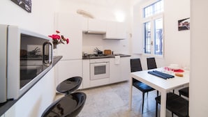 A compact kitchen with white cabinets, a stove, and a dining area with a table and chairs.