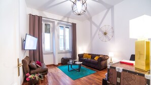 A living room with a sofa, a coffee table, a TV, and a lamp.
