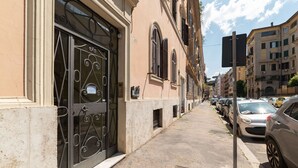 Une rue bordée de voitures garées et un bâtiment doté d’une grande grille en métal et de fenêtres.