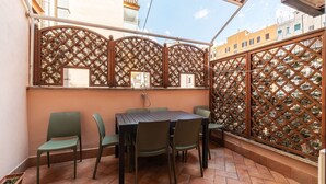 Une terrasse avec une table et des chaises, une clôture en métal et une vue sur les bâtiments.