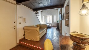 A room with a wooden ceiling, a sofa, a chair, and a table with a brass pot. - Historical Loft with view in city center! (Roma)