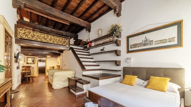 A bedroom with a bed, a staircase, and a dining area. - Historical Loft with view in city center! (Roma)