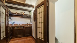 A narrow hallway with a tiled floor, wooden cabinets, and a door with a grid pattern. - Historical Loft with view in city center! (Roma)