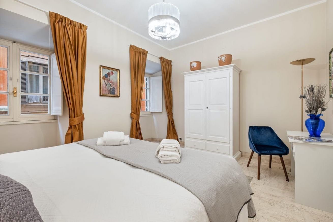 Une chambre à coucher comprenant un lit, une armoire, un bureau avec une chaise et une fenêtre avec des rideaux.
