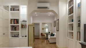 A hotel room with a bed, a dining area, and built-in bookshelves. - The Mirror Suite - Spanish Steps (Roma)
