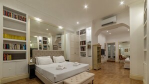 A spacious bedroom with a large bed, a bedside table, a wardrobe, and built-in bookshelves. - The Mirror Suite - Spanish Steps (Roma)
