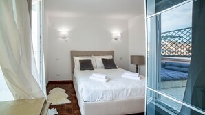 Un dormitorio con una cama, dos lámparas de pared, un ventanal y vistas a un balcón con una cama azul.