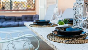 Una mesa de comedor dispuesta con platos, cubiertos y una copa.