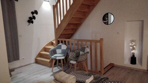 A staircase leading to a second floor, two patterned chairs, a small table, a mirror, and a decorative wall piece. - La Grange, in the heart of Périgord Noir, calm, serene and independent  (DAGLAN)