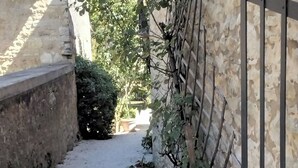 A narrow alleyway with a gravel path, a stone wall on the left, and a metal fence on the right. - La Grange, in the heart of Périgord Noir, calm, serene and independent  (DAGLAN)