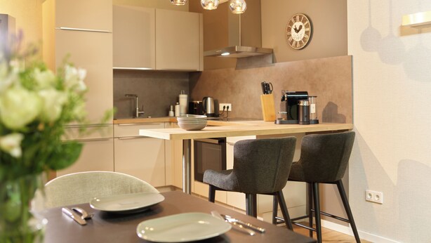 A modern kitchen with a central island, bar stools, and pendant lighting.