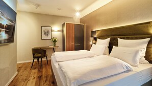 A hotel room with a bed, a desk, a chair, and a wardrobe.