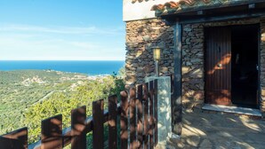 Un bâtiment en pierre avec une porte en bois, un mur en pierre et une vue sur la mer.