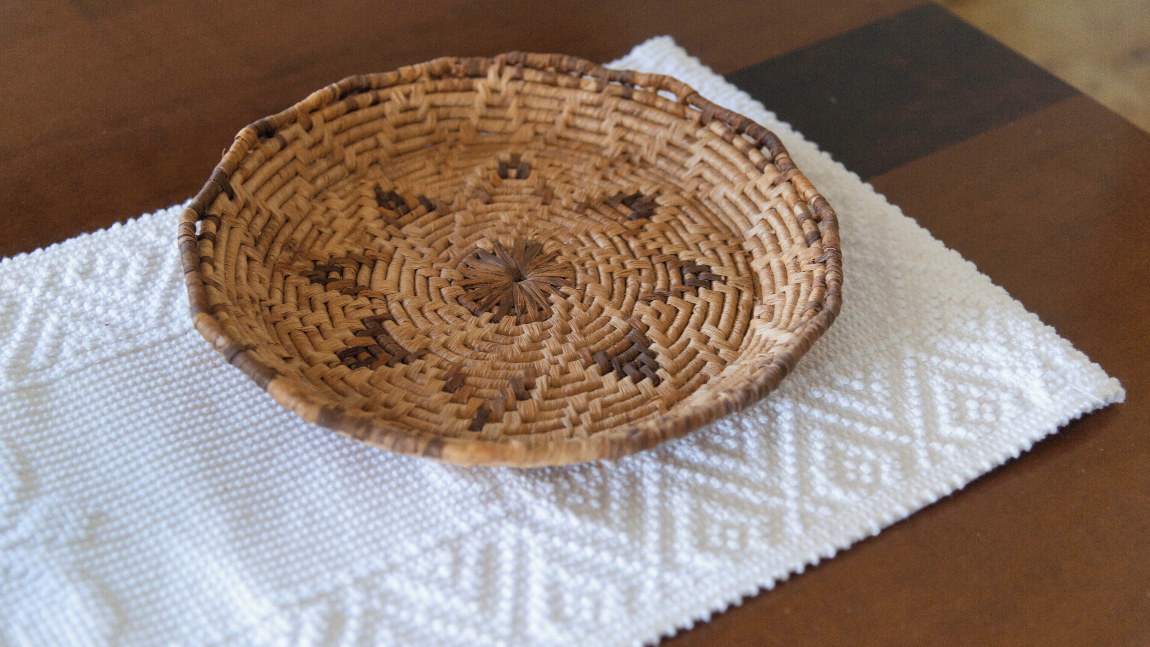 Un panier tressé posé sur un set de table blanc à texture.