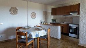 Une cuisine de taille réduite, dotée de meubles en bois, d’une cuisinière et d’un coin repas avec une table et des chaises.