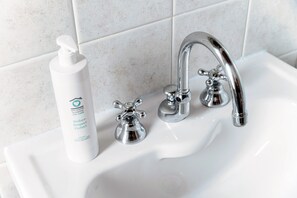 A bathroom sink with a chrome faucet and a bottle of hand soap. - Loft Madera (Como)