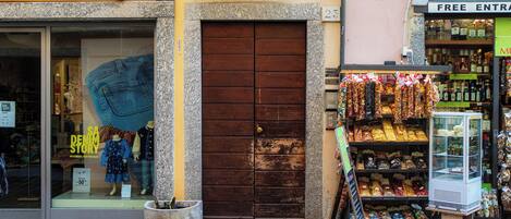 A storefront with a large wooden door, a mannequin in the window, and a display of snacks outside.