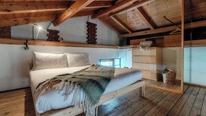 A wooden-framed room with a bed, a hanging lamp, and a brick stack. - Loft Madera (Como)