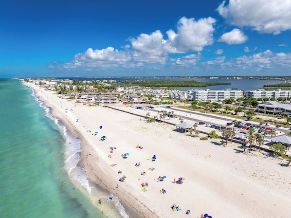 Un complejo turístico frente al mar con playa de arena, un puerto deportivo y villas con acceso directo a la playa.