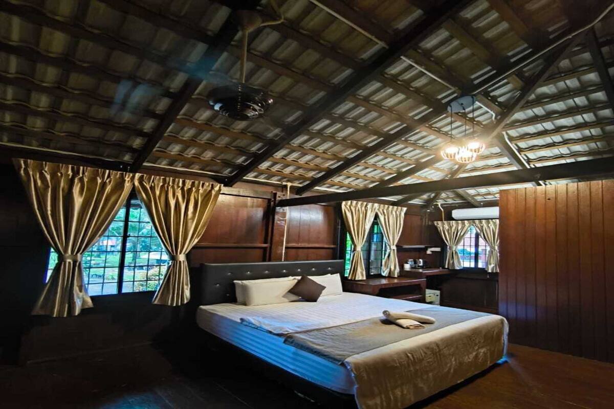 Une chambre avec un grand lit, des murs en bois et un plafond en pente.