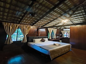 Ein Zimmer mit einem großen Bett, Holzwänden und einer schrägen Decke.