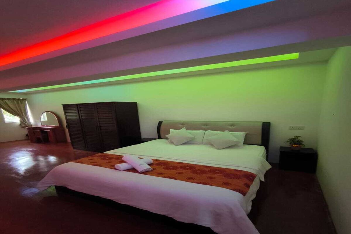 Une chambre d’hôtel avec un lit, une commode, un miroir et une fenêtre avec des rideaux.