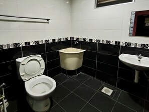 Un baño con inodoro, lavabo sobre pedestal y bidé.