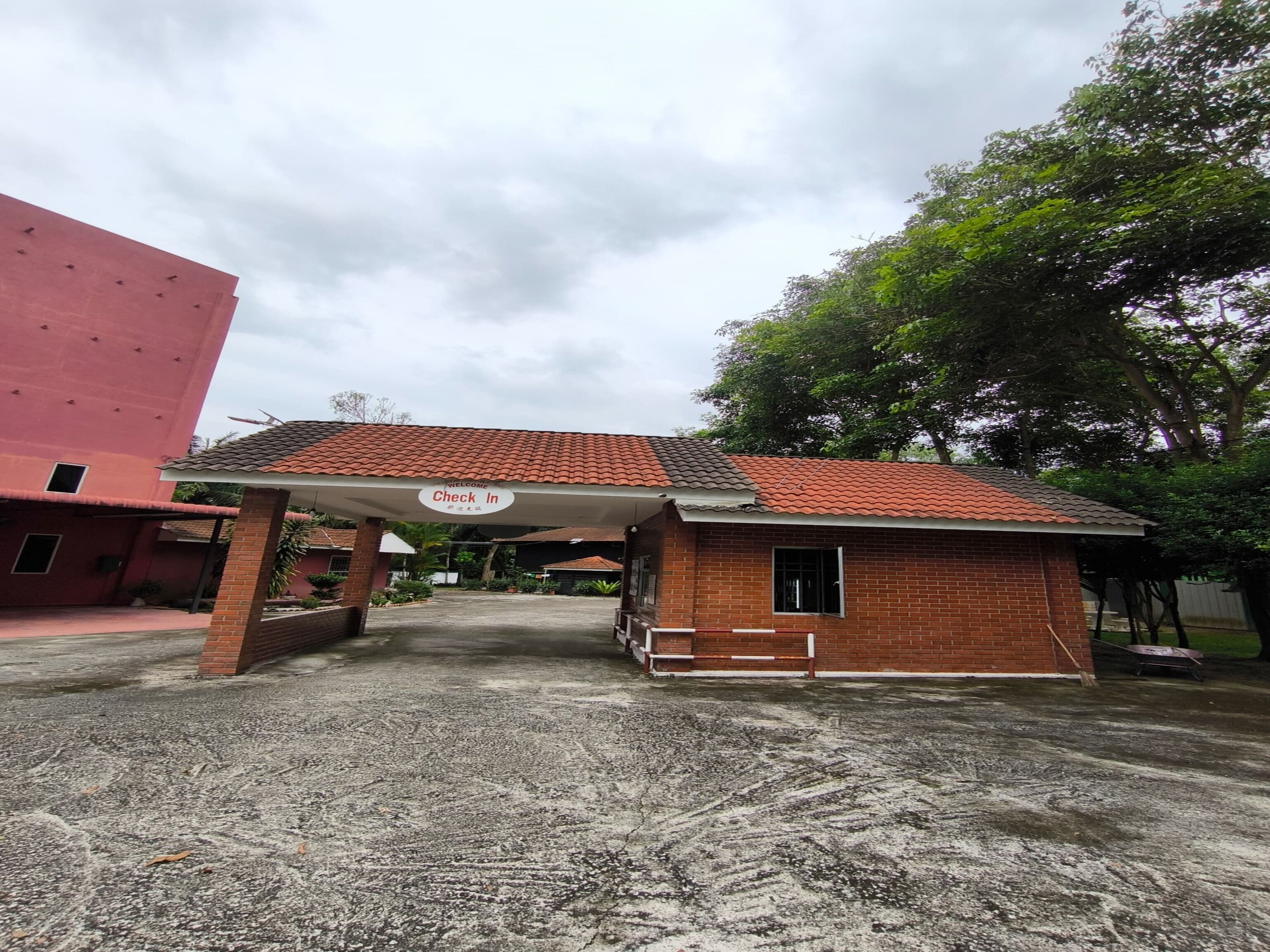 A building with a 'Check In' sign, a red brick structure, and a tiled roof.