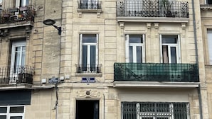 A multi-story building with a classic architectural style, featuring balconies with metal railings, a ground-floor entrance with a black door, and a visible street lamp. - Character apartment in Bordeaux - 78 m² - Saint-Seurin / Croix-Blanche (Bordeaux)