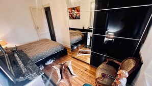 A compact bedroom with a bed, a dresser, a mirror, and a chair. - Character apartment in Bordeaux - 78 m² - Saint-Seurin / Croix-Blanche (Bordeaux)