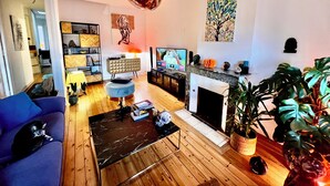 A modern living room with a sofa, a coffee table, a TV, a fireplace, and various decorative items. - Character apartment in Bordeaux - 78 m² - Saint-Seurin / Croix-Blanche (Bordeaux)