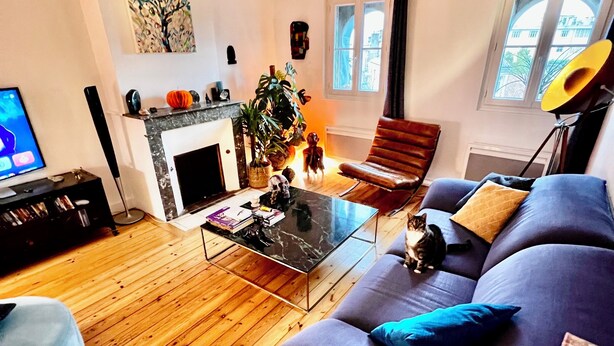 A living room with a fireplace, a sofa, a coffee table, and a television. - Character apartment in Bordeaux - 78 m² - Saint-Seurin / Croix-Blanche (Bordeaux)