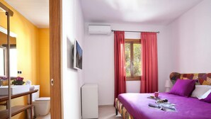 Une chambre à coucher comprenant un lit, un bureau, une chaise, une fenêtre avec des rideaux et un appareil de climatisation.