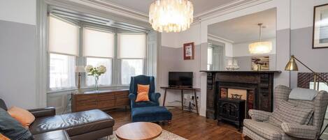 A living room with a fireplace, a blue armchair, a brown leather sofa, and a wooden coffee table.