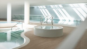 A modern indoor swimming pool with a circular hot tub, glass railings, and a wooden floor. - Beachfront holiday apartment, sauna, swimming pool (Pobierowo)